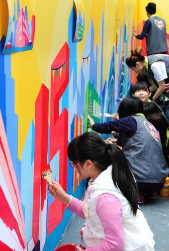 義工及受惠家庭一同為一幅以「市建局15周年」為主題的15米大型壁畫加上色彩。