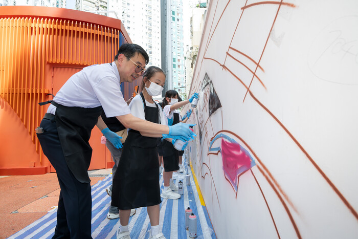 聖安多黎學校校長馬家健指導學生如何運用噴漆為壁畫填上顏色。